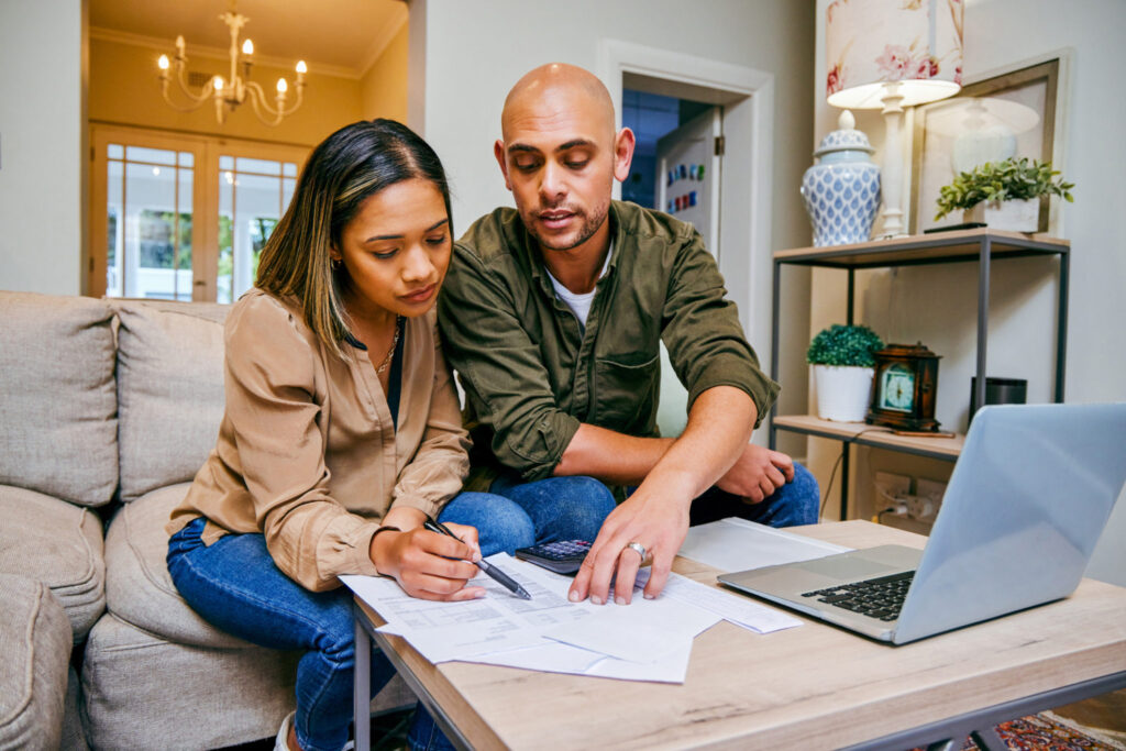 shot of a young couple reviewing their finances while using their laptop
